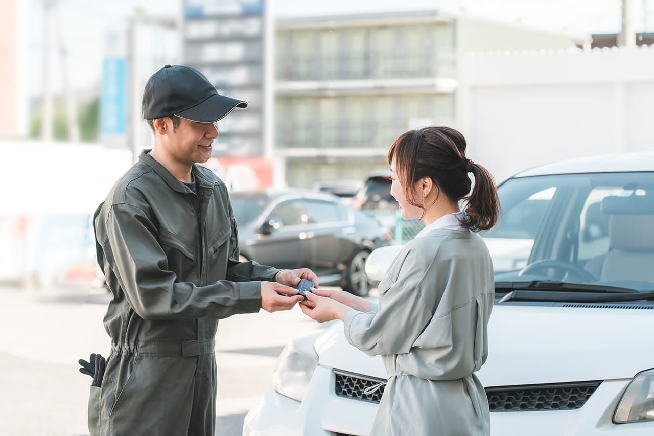男性整備士が自動車修理後に女性に車のカギを渡している様子