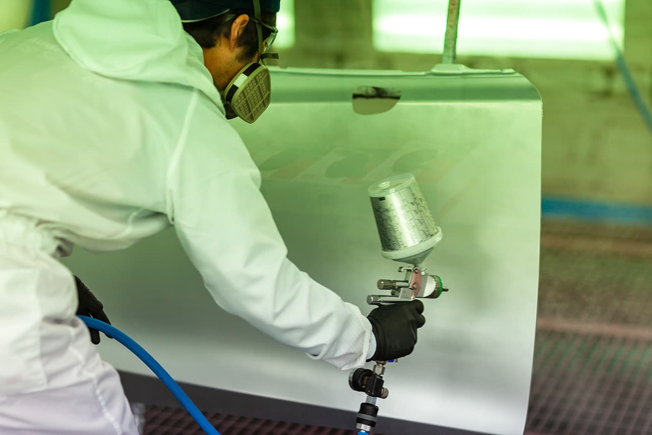 白い車のパーツを塗装している様子